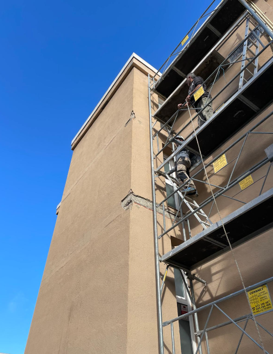 Operarios trabajando en el andamio sobre la fachada del edificio